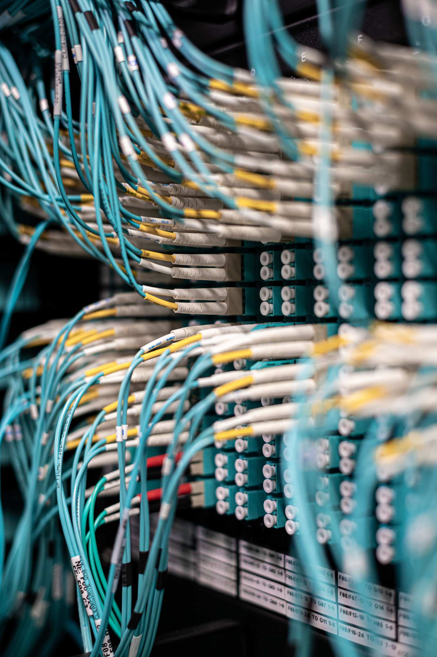 Server racks in a data hall with blue cables in a patch panel